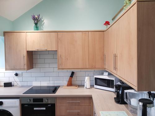 a kitchen with wooden cabinets and a microwave at Charming 3-Bed Apartment in Scarning Near Dereham in East Dereham