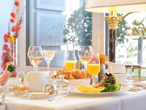 The Dufour by Hotel Schweizerhof Zürich في زيورخ: طاولة مع طبق من الطعام وكؤوس من النبيذ