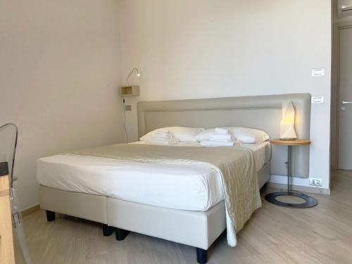 a bedroom with a white bed and a table with a lamp at Daedalium in Marina di Palma