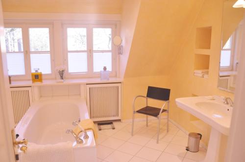 a bathroom with a tub and a sink and a chair at Apartment am Bürgerpark in Bremerhaven