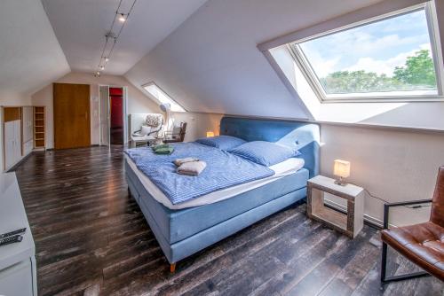 Schlafzimmer mit einem blauen Bett und einem großen Fenster in der Unterkunft Ferienhaus CAMILLO in Büllingen