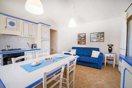eine Küche und ein Wohnzimmer mit einem Tisch und einem blauen Sofa in der Unterkunft Le Case di Maiorca - PMS CaseVacanze in Budoni