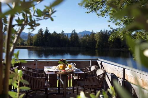 a table with chairs sitting on a deck next to a lake at Hotel-Pension Seebad "Seegenuss-Natur-Spa" in Sulzberg