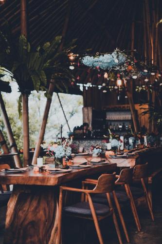 a long wooden table with chairs and flowers on it at Desa Eko in Munduk
