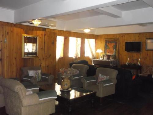 a living room with couches and chairs and wooden walls at Keimoes Hotel in Keimoes
