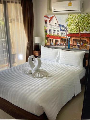 a bed with two white swans on top of it at Mai Khao Beach Apartments -MBC- in Ban Bo Sai Klang