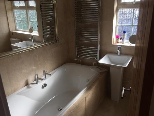 a bathroom with a white tub and a sink at 9 Chudleigh Close in Bedford