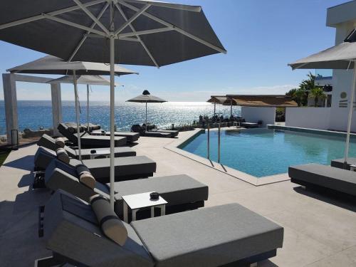 a swimming pool with chairs and umbrellas next to a resort at Akrotiri Olympus Luxury Suites - Adults Only in Plaka Litochorou