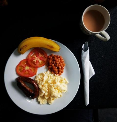 a plate of food with a banana and beans and a cup of coffee at Fawlty Towers Accommodation & Activities in Livingstone
