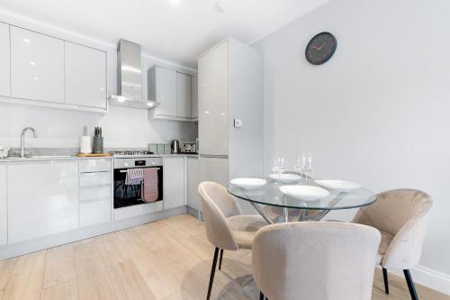 a white kitchen with a glass table and chairs at 2 Bedroom Penthouse with parking High Wycombe By 360Stays in High Wycombe