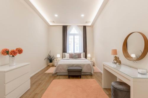 a white bedroom with a bed and a mirror at Exclusive Csengery Residence in the heart of Budapest in Budapest