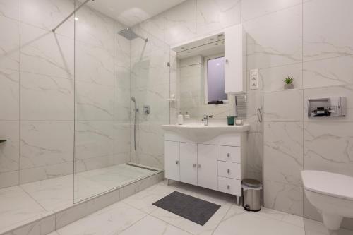 a white bathroom with a sink and a shower at Exclusive Csengery Residence in the heart of Budapest in Budapest