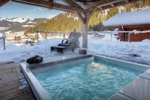a hot tub in the snow on a deck at Chalet Ruisselet - OVO Network in Châtel