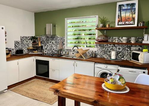 eine Küche mit weißen Schränken und einem Holztisch in der Unterkunft Ti Kay Ilets in Les Trois-Îlets