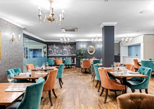 a restaurant with wooden tables and chairs and a chandelier at Dukes Head Hotel Kings Lynn in Kings Lynn