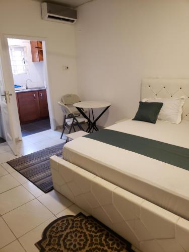 a bedroom with a large bed and a table at Hgl Guest House in East Legon