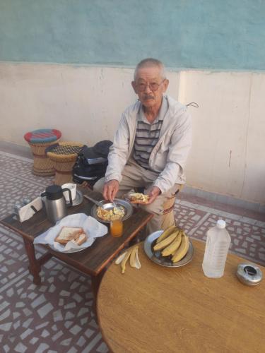 an older man sitting at a table with a tray of food at S A HAVELI GUEST HOUSE in Bikaner