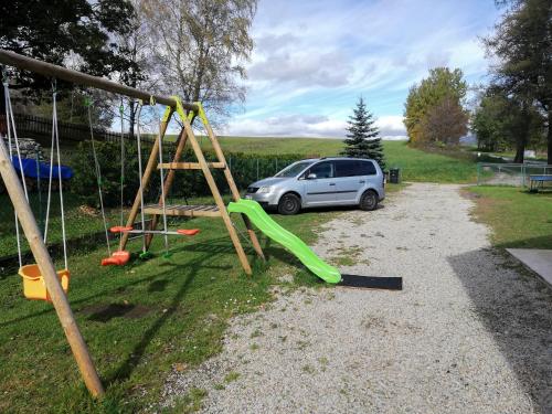 a car parked next to a playground with a swing at Pohoda u Lva in Nová Pec