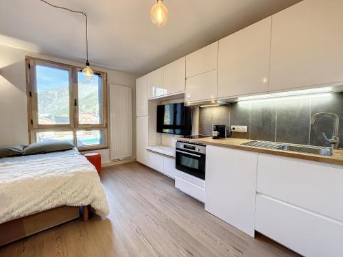 - une cuisine avec des placards blancs et un lit dans une chambre dans l'établissement Superbe studio refait à neuf et tout équipé avec parking, à Chamonix-Mont-Blanc