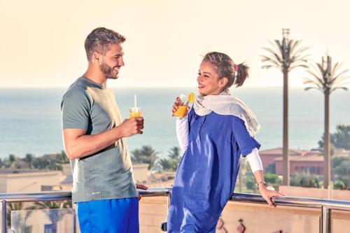 un homme et une femme debout sur un balcon avec des boissons dans l'établissement فندق مروج نجد, à Djeddah