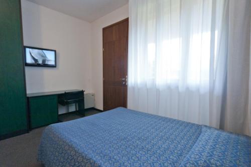 Un dormitorio con una cama azul y una ventana en Hotel Campana, en Reggio Emilia