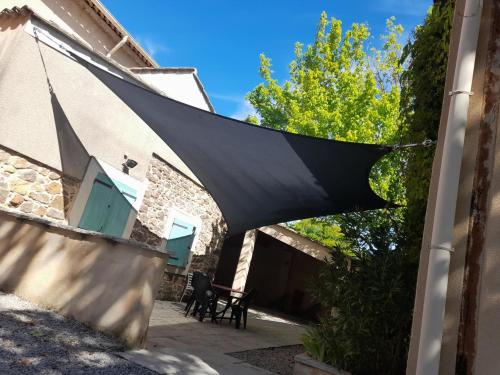 une voile d'ombrage noire suspendue au côté d'un bâtiment dans l'établissement Le laurier aux esperifes, à Vidauban