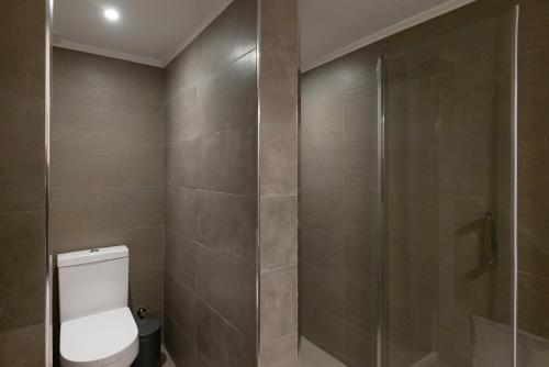 a bathroom with a toilet and a glass shower at Grammata Suites in Ermoupoli