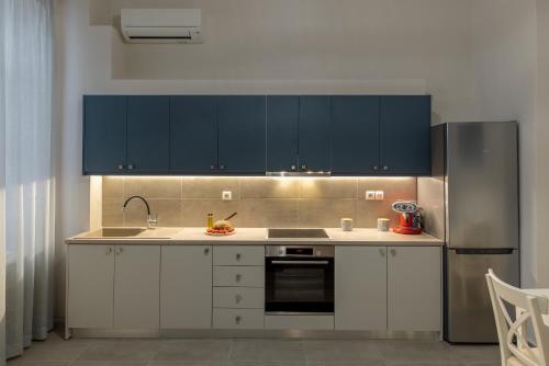 a kitchen with white cabinets and a black refrigerator at Grammata Suites in Ermoupoli