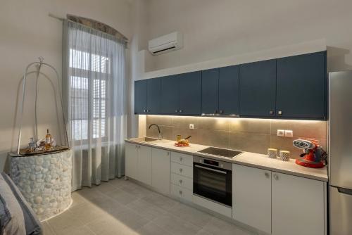 una cocina con armarios blancos y electrodomésticos negros en Grammata Suites, en Ermoupoli