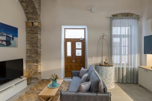 a living room with a blue couch and a tv at Grammata Suites in Ermoupoli