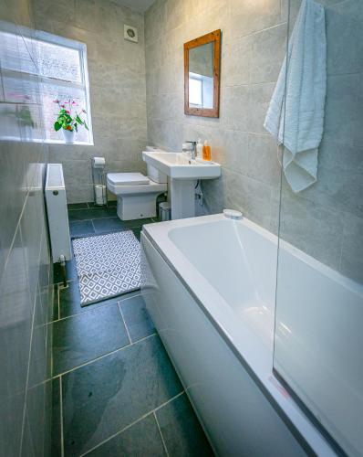 a bathroom with a bath tub and a sink at Spacious Ground Floor Apartment in Keswick