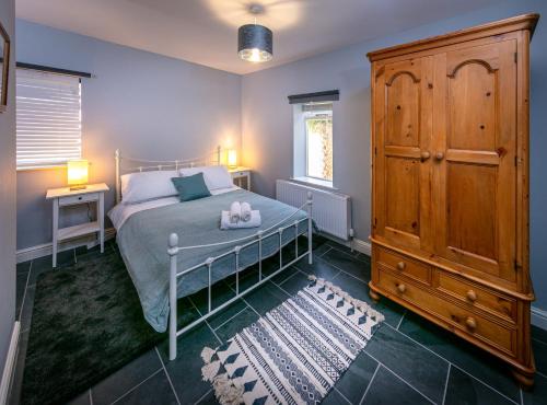a bedroom with a bed and a wooden cabinet at Spacious Ground Floor Apartment in Keswick