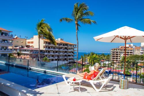 a woman sitting in a chair next to the pool at a resort at Casa Doña Susana in Puerto Vallarta