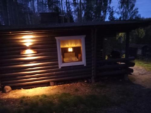 a log cabin with a window in the night at Mökki Salakka Rääkkylä Pohjois-Karjala in Nieminen
