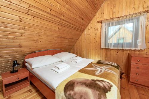 um quarto com uma cama num quarto de madeira em Ośrodek Rekreacyjny Aga em Gąski