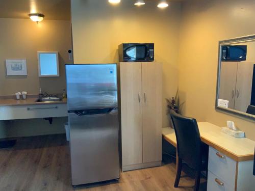 a kitchen with a refrigerator and a sink and a desk at Motel Rayalco in Laurier Station