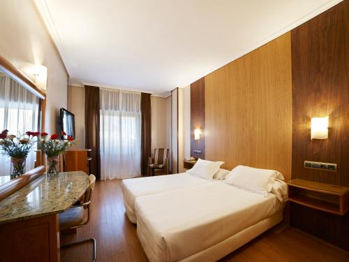 um quarto de hotel com uma cama grande e uma secretária em Zenit Dos Infantas em Zamora
