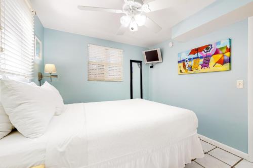 a white bed in a blue room with a ceiling fan at Southernmost Retreat in Key West