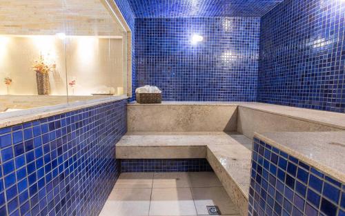 a blue tiled bathroom with a tub and a shower at Flat Hotel Vision Hplus frente para Esplanada - SEM CAFÉ - Acomodação Particular in Brasilia