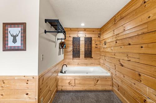 a bathroom with a wooden wall and a tub at The Sly Fox - Recently Updated/ Ideal PF Location in Pigeon Forge