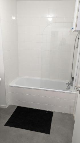 eine Dusche mit einer weißen Badewanne und einem schwarzen Teppich in der Unterkunft Chambre dans appartement près du Roazhon Park in Rennes