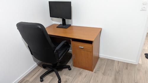 einen Schreibtisch mit einem Computermonitor und einem schwarzen Stuhl in der Unterkunft Chambre dans appartement près du Roazhon Park in Rennes