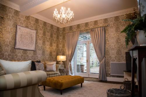 a living room with a chandelier and a couch and a chair at Stable Cottage in Ashbourne