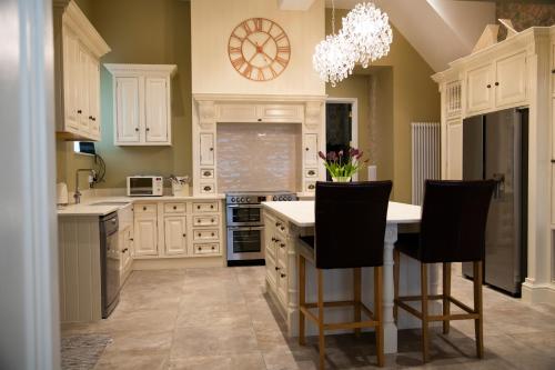 a kitchen with white cabinets and a table with chairs at Stable Cottage in Ashbourne