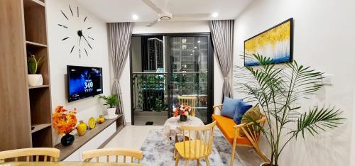 ein Wohnzimmer mit einem Tisch, Stühlen und einer Uhr in der Unterkunft NK#Homestay#Vinhomes#Oceanpark#2PN#C22 in Gia Lâm Pho