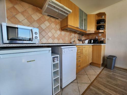 a small kitchen with a microwave and a refrigerator at Le Green - Appt Houlgate vue sur le golf in Houlgate