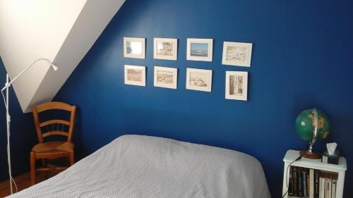 een slaapkamer met een blauwe muur met een bed en een stoel bij WIM GOLF in Wimereux