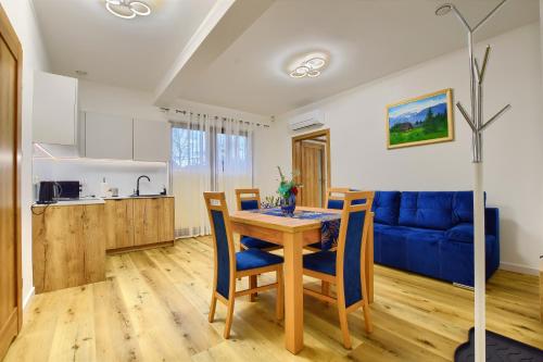 uma cozinha e uma sala de jantar com uma mesa e um sofá azul em Apartamenty Bianka em Wisla
