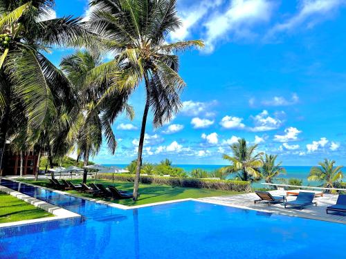 einen Pool in einem Resort mit Palmen und dem Meer in der Unterkunft Casa da Gameleira in Baía Formosa