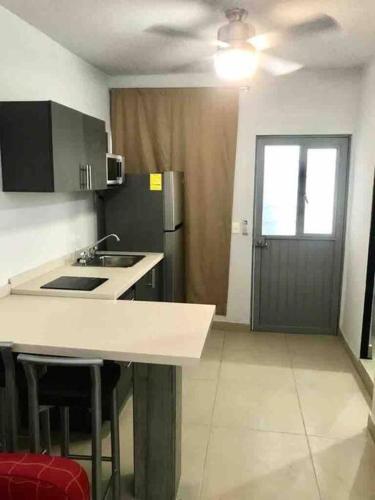 a kitchen with a counter and a refrigerator and a door at Loft Hermoso en Guadalupe in Monterrey